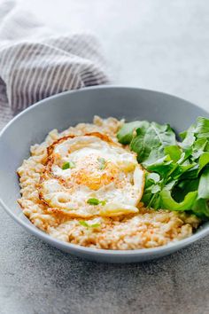 a bowl filled with rice, spinach and an egg in it on top of a table