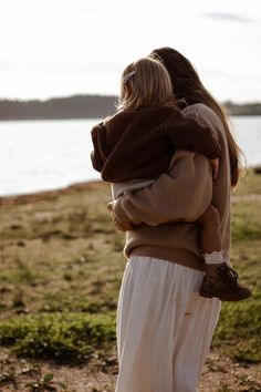 two women are walking on the beach with their arms around each other as they hug