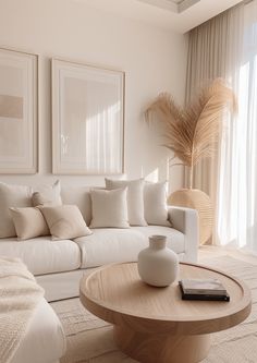 a living room filled with white furniture and pillows on top of a wooden coffee table