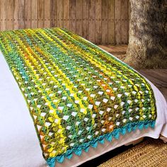 a crocheted bedspread on top of a bed in a room with wood walls