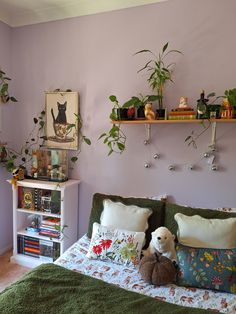 a bedroom with purple walls and plants on the shelves above the bed, along with a teddy bear