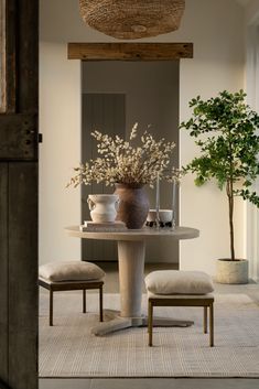 a dining room table with two chairs and a vase filled with flowers sitting on top of it