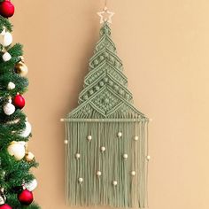 a christmas tree hanging from the side of a wall next to a small green crocheted house ornament