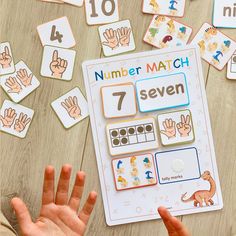 a child's hand next to a number match game on a table with matching numbers