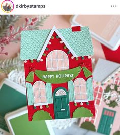 a hand holding up a house shaped card with the words happy holidays written on it