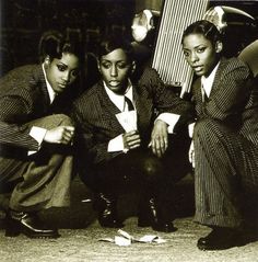 three women in suits sitting on the ground