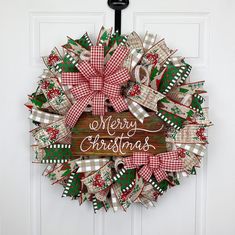 a christmas wreath hanging on a door with the words merry christmas written on it in red, white and green