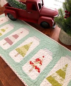 a red toy truck sitting next to a christmas tree