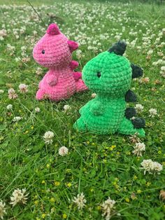 two crocheted dinosaurs sitting in the grass