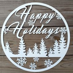 a happy holidays sign on a wooden surface with snowflakes and trees in the background