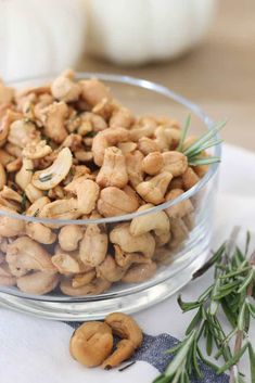 a glass bowl filled with cashews sitting on top of a white table cloth