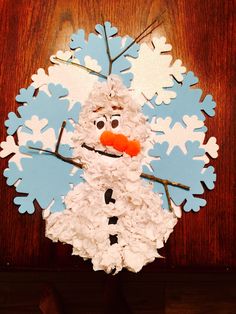 a snowman made out of paper on top of a wooden table