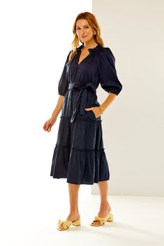 Our best-selling Fanny Dress is back! Cut in a cotton blend fabric, this flowing, solid midi dress features 3/4 balloon sleeves, front v neck, ruffle detail at the neck and skirt tiers, side seam pockets, and a waist sash with ricrac trim. Pair with flats or heels for an effortless, summer to fall look. Tiered maxi dress V neck with ruffle collar 3/4 raglan balloon sleeves with elastic cuffs Waist sash with ricrac trim Side seam pockets This item runs large. We recommend sizing down. Made in USA 3/4 Sleeve Ruffled Dress For Work, Workwear Dress With Ruffles And 3/4 Sleeves, Cotton Puff Sleeve Dress With Ruffles V-neck, Summer Midi Dress With Ruffles And 3/4 Sleeves, Spring Midi Dress With 3/4 Sleeves And Ruffles, Chic Midi Dress With 3/4 Sleeves And Ruffles, Cotton Ruffle Dress With 3/4 Sleeves, Cotton Dresses With Ruffles And 3/4 Sleeve, Cotton Dress With Ruffles And 3/4 Sleeves