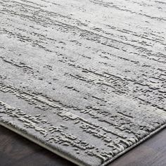 an area rug on the floor with wooden floors and dark colored wood in the background