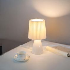 a table lamp sitting on top of a desk next to a cup and saucer