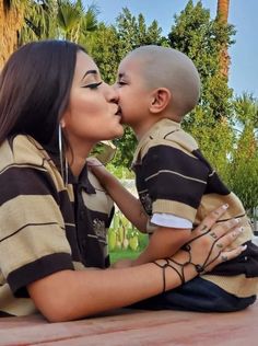 a woman kissing a young boy on the cheek with palm trees in the back ground