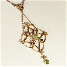 The colors of the holiday's sparkle in this Edwardian necklace! Hand crafted in 9 karat gold, this necklace is set with two sparkling green peridot gems and five bright red garnets. The drop of this necklace is 63 mm long and 33 mm across and the chain measures 14.5 inches long and closes with a barrel clasp. The necklace is marked '9c' for 9k gold. The gold has a rosy hue. This necklace weighs 7 grams. Made in England around 1900-1910. This lovely necklace has a light and airy feel and yet is s May Birthstone Multi-stone Pendant Necklace, Yellow Gold Multi-stone Necklace For May Birthstone, Formal Peridot Pendant Necklace, Fine Jewelry Green Multi-stone Necklace, Green Multi-stone Fine Jewelry Necklace, Green Multi-stone Fine Jewelry Necklaces, Gold Multi-stone Necklace For May Birthstone, Peridot And Garnet, Edwardian Necklace