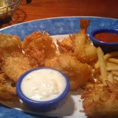 fried fish and french fries on a blue plate with dipping sauce in a bowl next to it