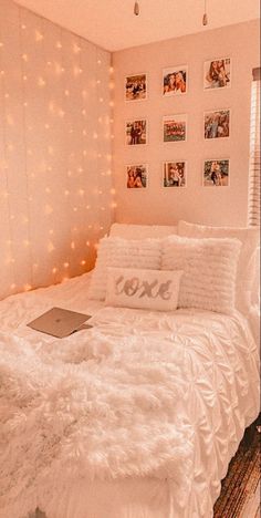 a white bed in a bedroom with pictures on the wall and lights hanging above it