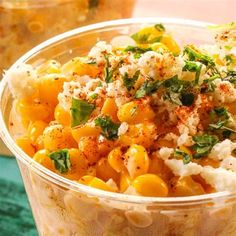 a plastic container filled with macaroni and cheese on top of a green table