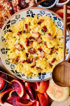 a bowl filled with scrambled eggs next to sliced peaches and other food on a table