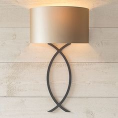 a wall mounted lamp with a white shade on it's side and a wooden background