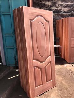 wooden doors are lined up outside in front of a brick wall and door with an oval design on it