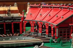 a lego model of a train station with red and green sidings on the roof