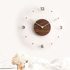 there is a clock on the wall above a vase with flowers in it and a white background