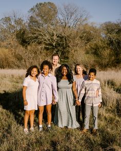 a group of children standing in a field with their arms around each other and smiling at the camera