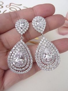 This earring features a large halo Luxury Cubic Zirconia detailed teardrop set and surrounded by 3 layers of cubic zirconia crystals, dangle from a teardrop posts with rhodium plated brass settings. Size: Length of Earring from top of Ear wire is approx 2.1 inches or 5.2 cm Each earring weighs 9 gms Teardrop Earrings Wedding, Bridal Jewlery, Anting Manik, Diamond Facts, Bridal Diamond Jewellery, Earrings White, Fabulous Jewelry, Antique Earrings, Bridal Pearls