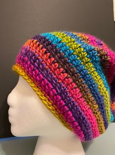 a multicolored crocheted hat on top of a mannequin head