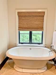 a white bath tub sitting under a window in a bathroom