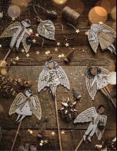 christmas decorations with angels and stars on wooden table next to string spools filled with glitter