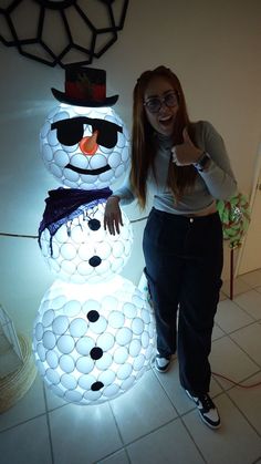 a woman standing next to a lighted snowman