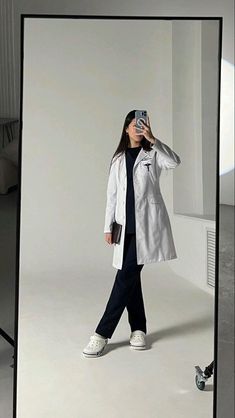 a woman taking a photo with her cell phone in front of a white wall and floor