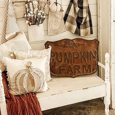 a white bench with pillows and pumpkins hanging on the wall next to other items