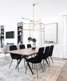 a dining room table with black chairs and a white rug