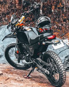 a black motorcycle parked on top of a dirt road next to a pile of rocks