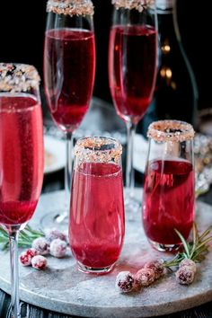 three wine glasses filled with red liquid and sprinkles on a marble platter