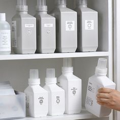 a person is holding a bottle in front of several bottles on the shelve