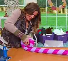 a woman is holding a large pink and white candy cane in front of a table