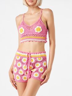 a woman is wearing pink and yellow crochet shorts with flowers on the bottom