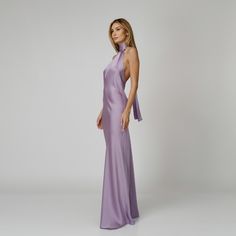 A captivating blend of elegance and allure, our Lylia Open Back Halter Dress exudes undeniable charm. Tailored with a flattering bias cut from lavender double silk satin, it drapes gracefully over the silhouette. The halter neckline delicately frames the shoulders, while the revealing back adds a note of sensuality. For a playful and feminine look, you can transform the silk tie neck into a chic bow, or you can let it drape loosely, adding a touch of laid-back sophistication to your ensemble.  W Purple Silk Dresses, Lavender Formal Dress Long, Satin Lavender Bridesmaid Dresses, Satin Purple Dress, Halter Neck Satin Dress, Satin Open Back Dress, Elegant Purple Dress, Lavender Satin Dress, Halter Silk Dress