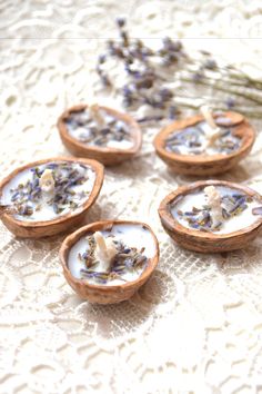 four wooden bowls filled with flowers on top of a lace covered table cloth next to dried plants