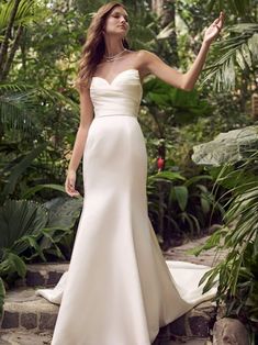 a woman in a white wedding dress standing on some steps with her arms out to the side