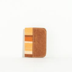 an orange and yellow striped wallet sitting on top of a white table next to a wall