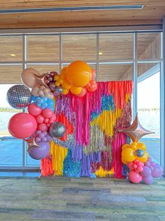 balloons and streamers are hanging from the ceiling in front of a large window with an ocean view