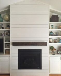 a living room with white painted walls and built - in shelving, including a fireplace