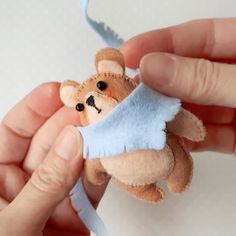 a person holding a small stuffed animal in their hand with a blue ribbon around it